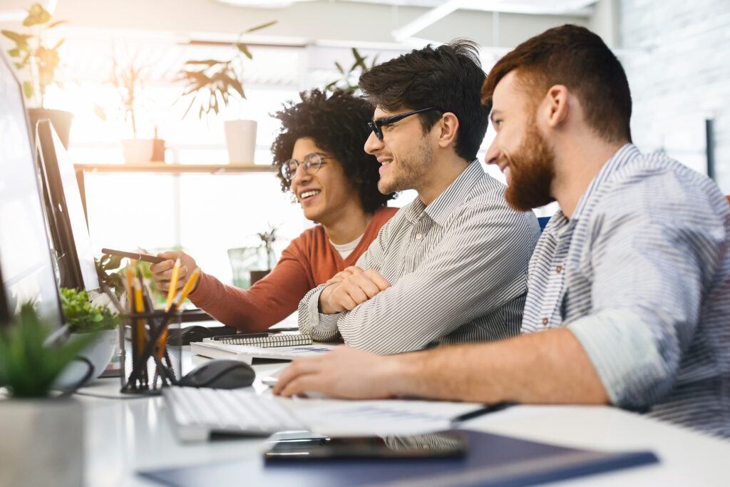 Three men enjoying good coding job on computer at modern office